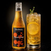 A bottle of KimBeAu Passion Fruit non-alcoholic spirit next to a highball glass filled with a golden amber drink, ice, a lemon slice, and a small herb garnish, set against a dark background.