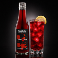 A bottle of KimBeau Sorrel Drink next to a tall glass filled with a red sorrel drink and ice, garnished with a lemon slice, on a black reflective background.